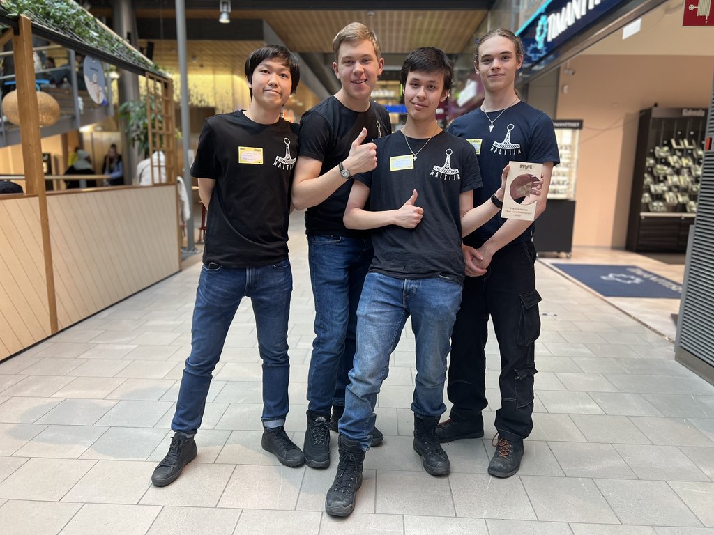 Neljä nuorta seisoo ja poseeraa kameralle, yksi nuorista pitelee palkintopokaalia.