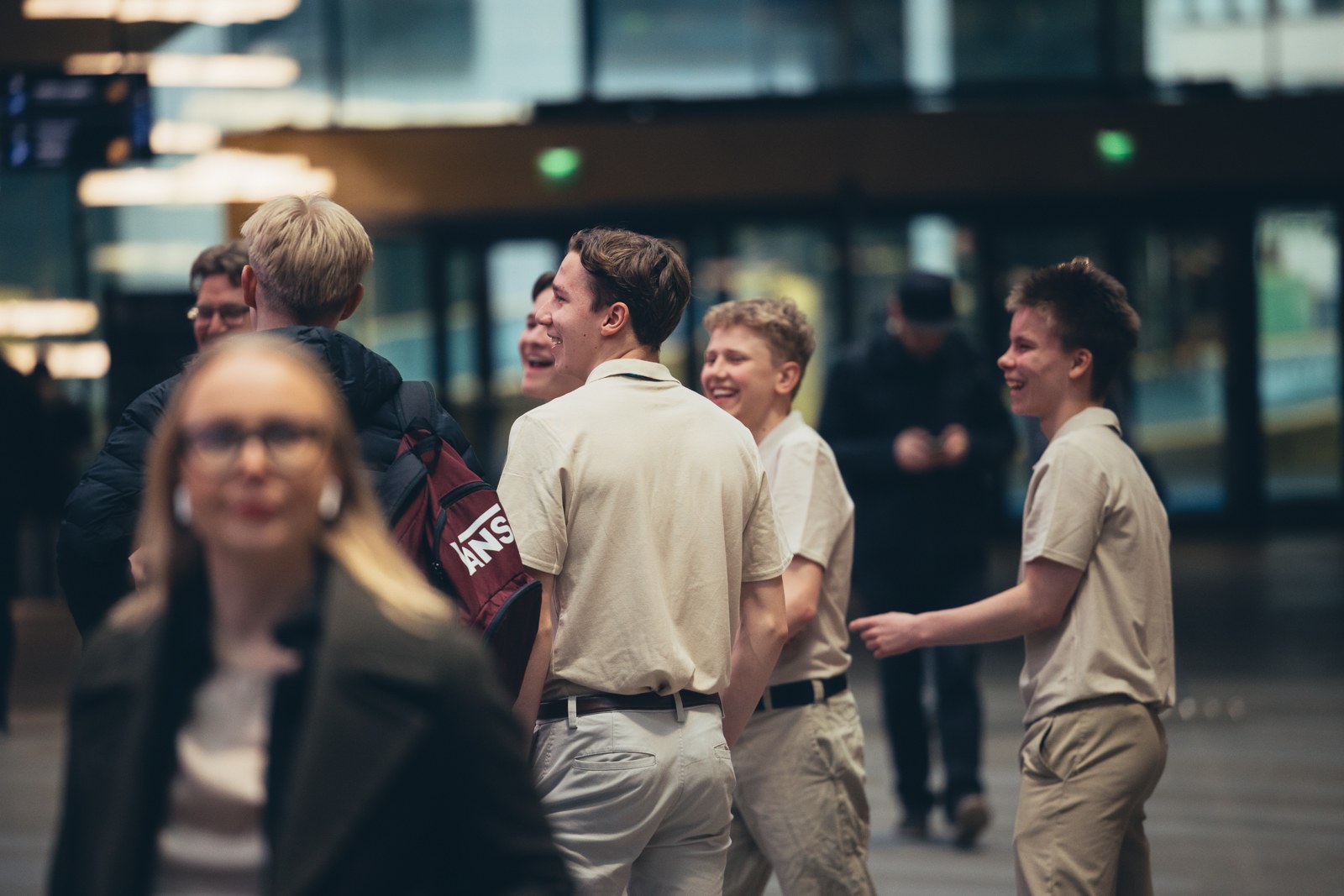 Kolme iloista nuorta seisoo ja katsoo vasemmalle.