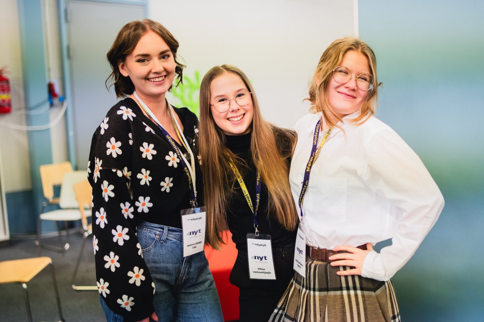 Kolme nuorta hymyilevät kameralle rivissä.