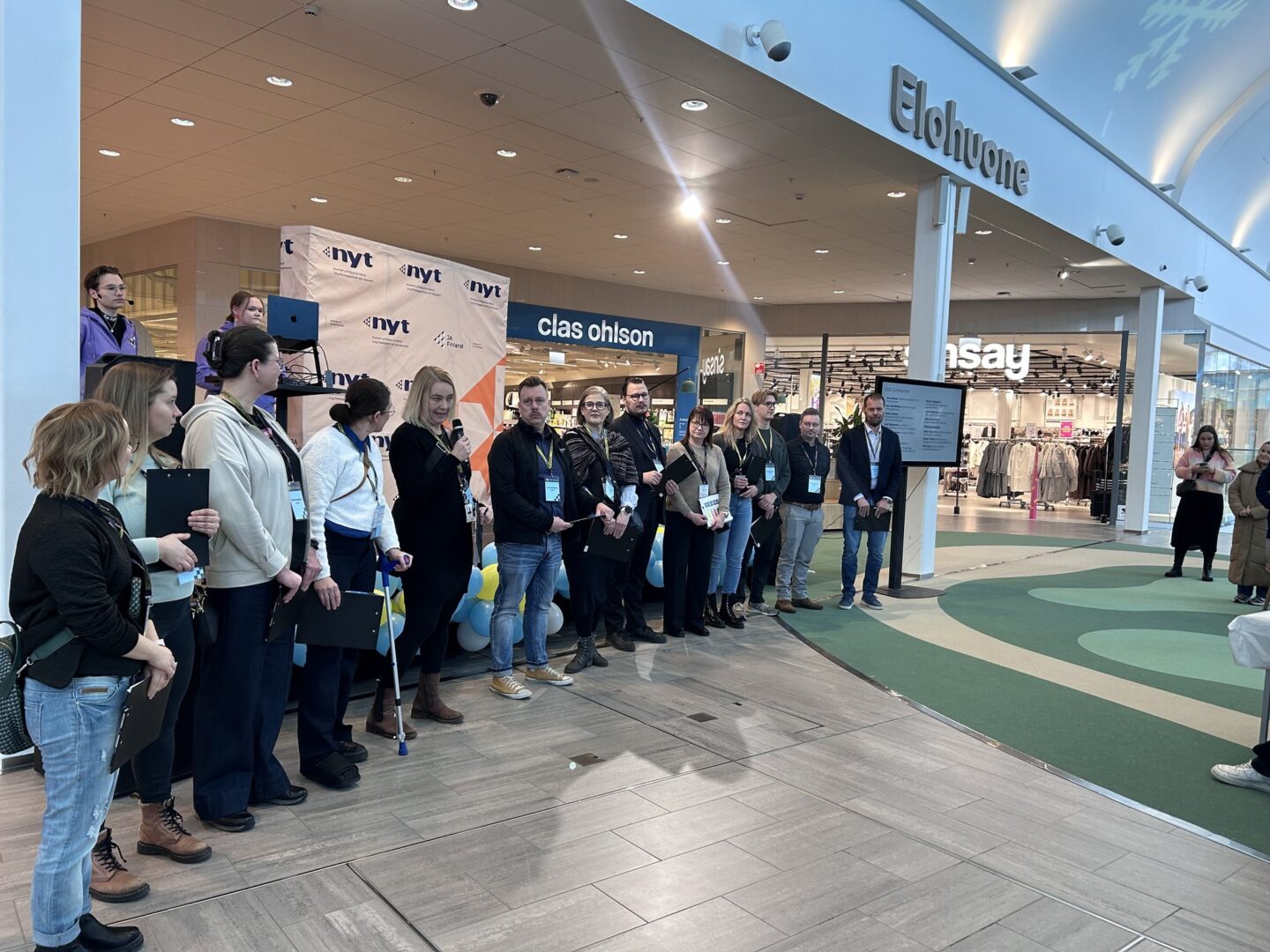 Joukko ihmisiä seisoo ryhmässä tapahtumalavalla.