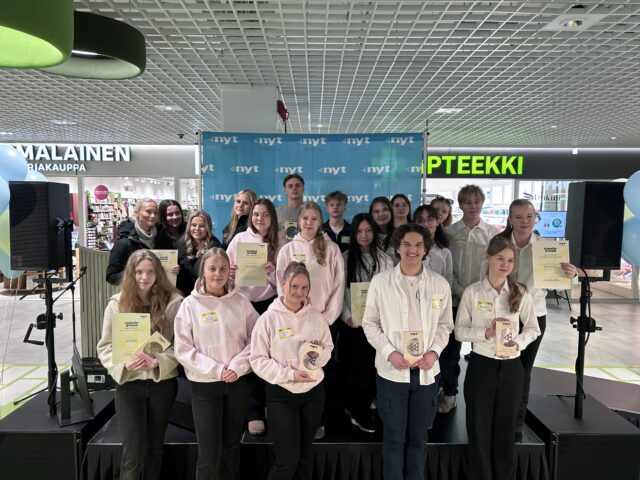 Ryhmä nuoria yhteiskuvassa lavalla pokaaleja käsissään.