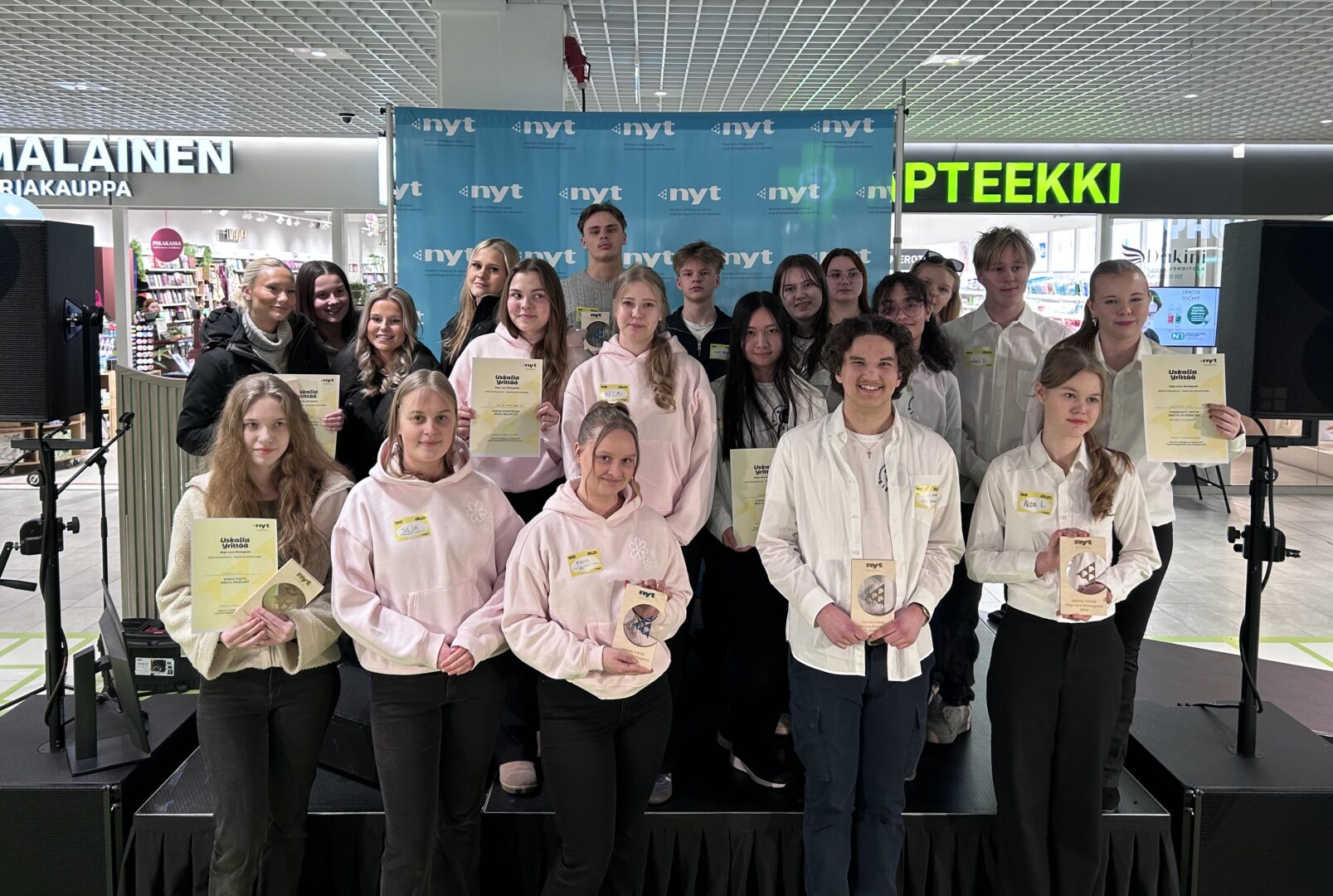 Ryhmä nuoria yhteiskuvassa lavalla pokaaleja käsissään.