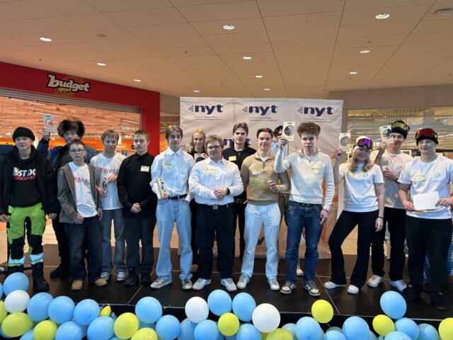 Joukko nuoria seisoo lavalla palkintojen kanssa ja hymyilee kameralle.