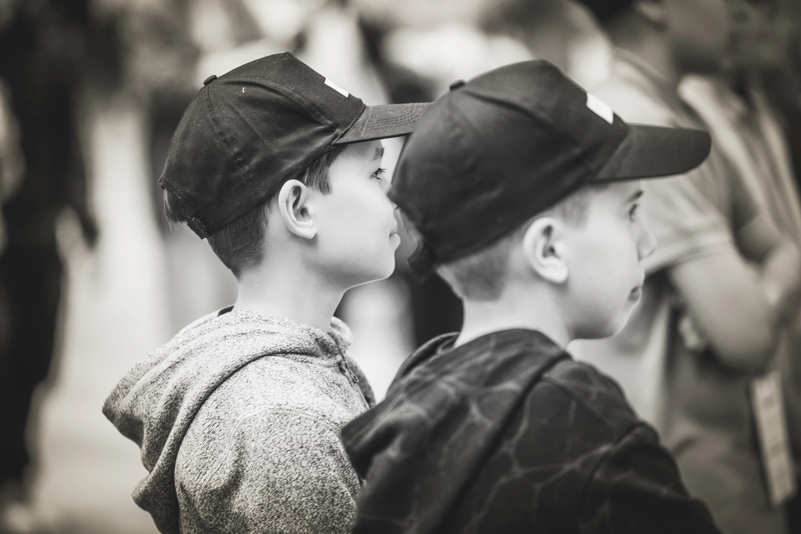 Kaksi lasta katsoo pois kamerasta, molemmilla on lippalakki päässä.