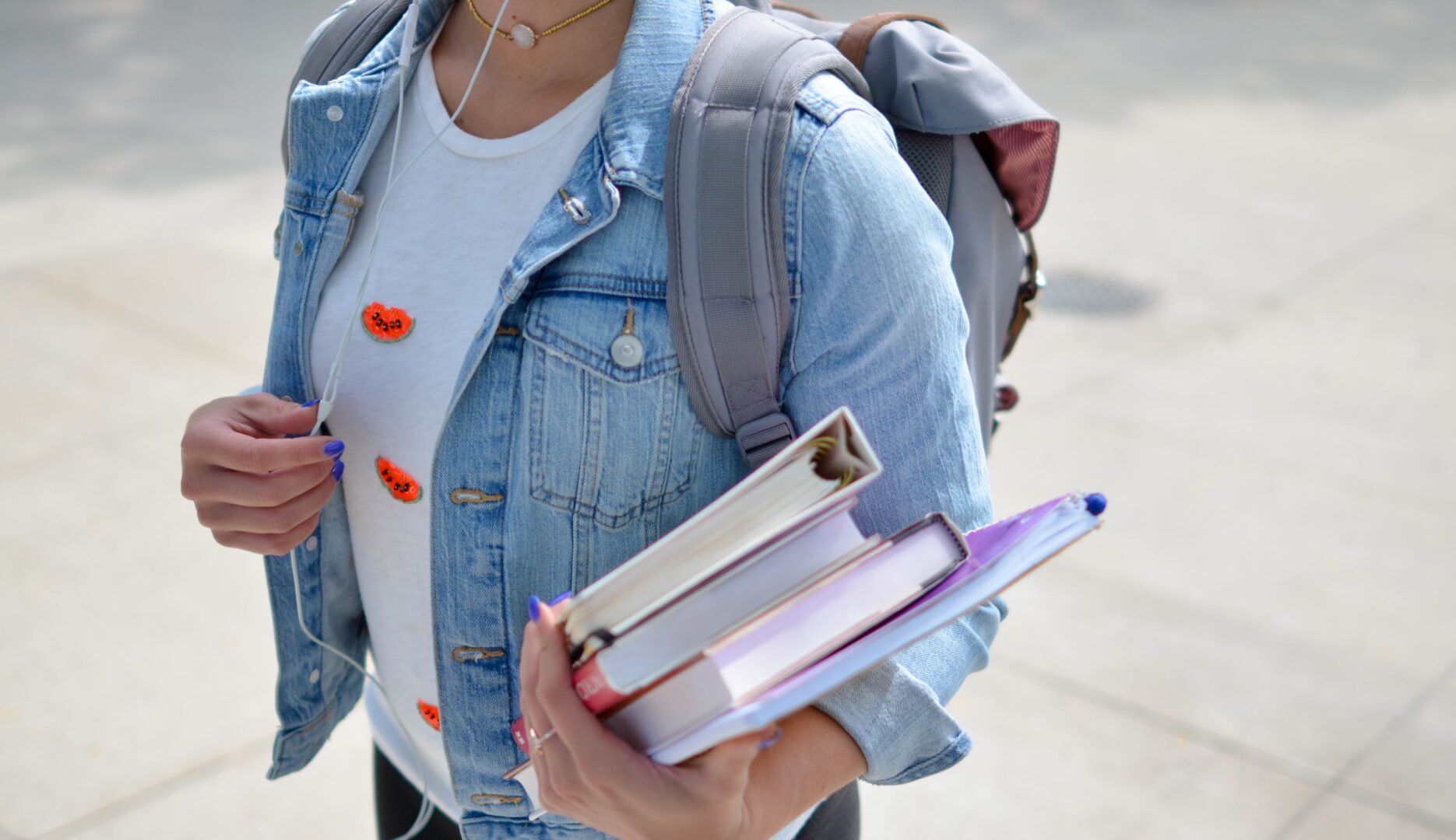 Kuvituskuva, jossa näkyy farkkutakkiin pukeutunut nuori, jolla on kädessään kirjoja