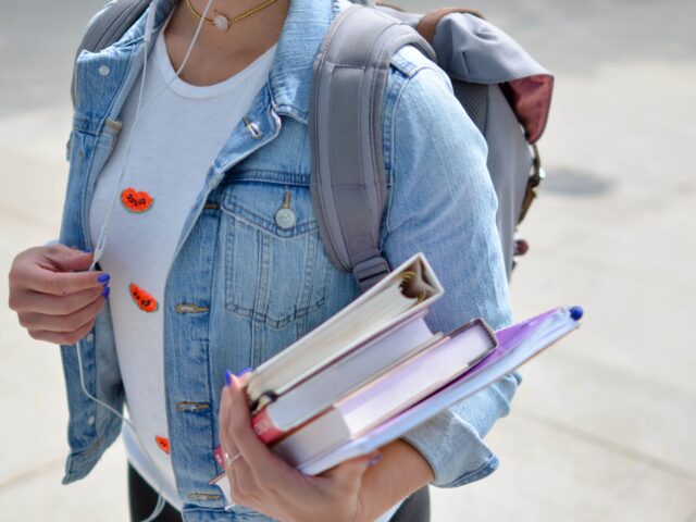 Kuvituskuva, jossa näkyy farkkutakkiin pukeutunut nuori, jolla on kädessään kirjoja