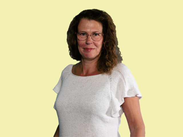 Kuvassa henkilö hymyilee kameralle, tausta on keltainen.